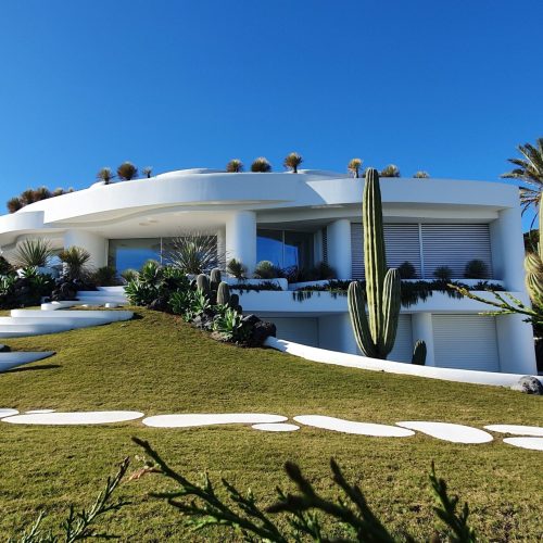 Home Contemporary white villa with garden and cacti in Dénia, Spain under a clear blue sky.